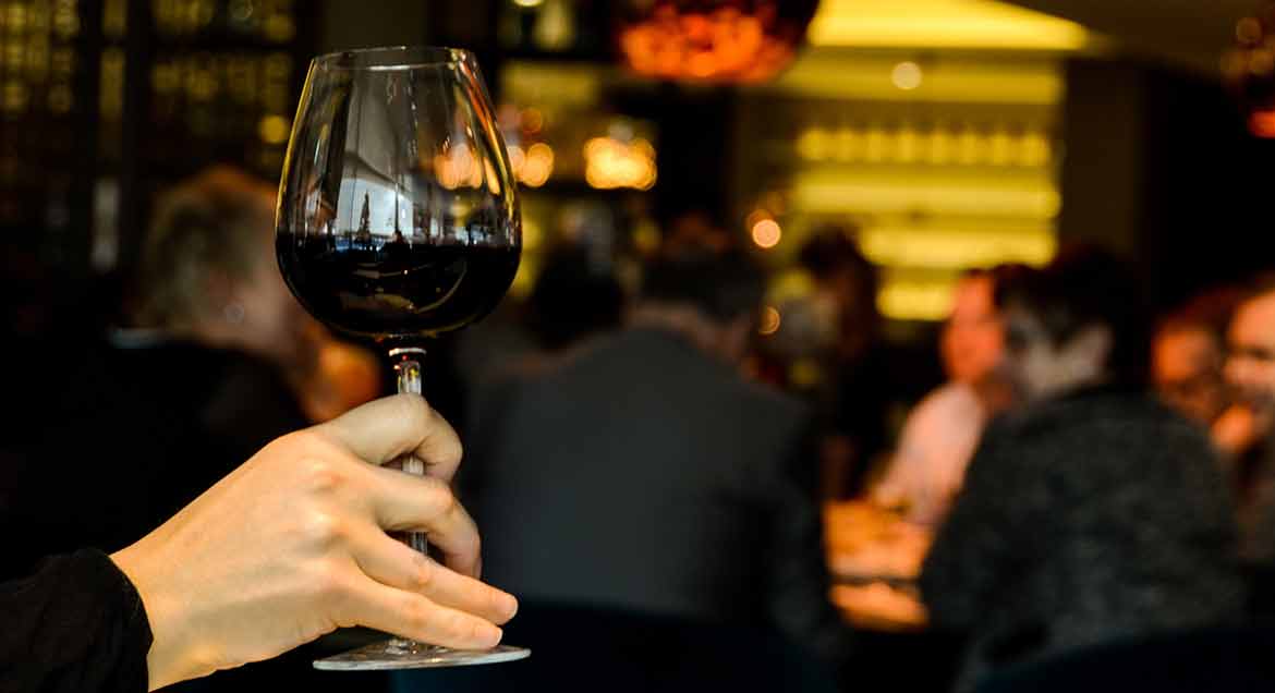 Glass of Pinot Noir wine held at happy hour